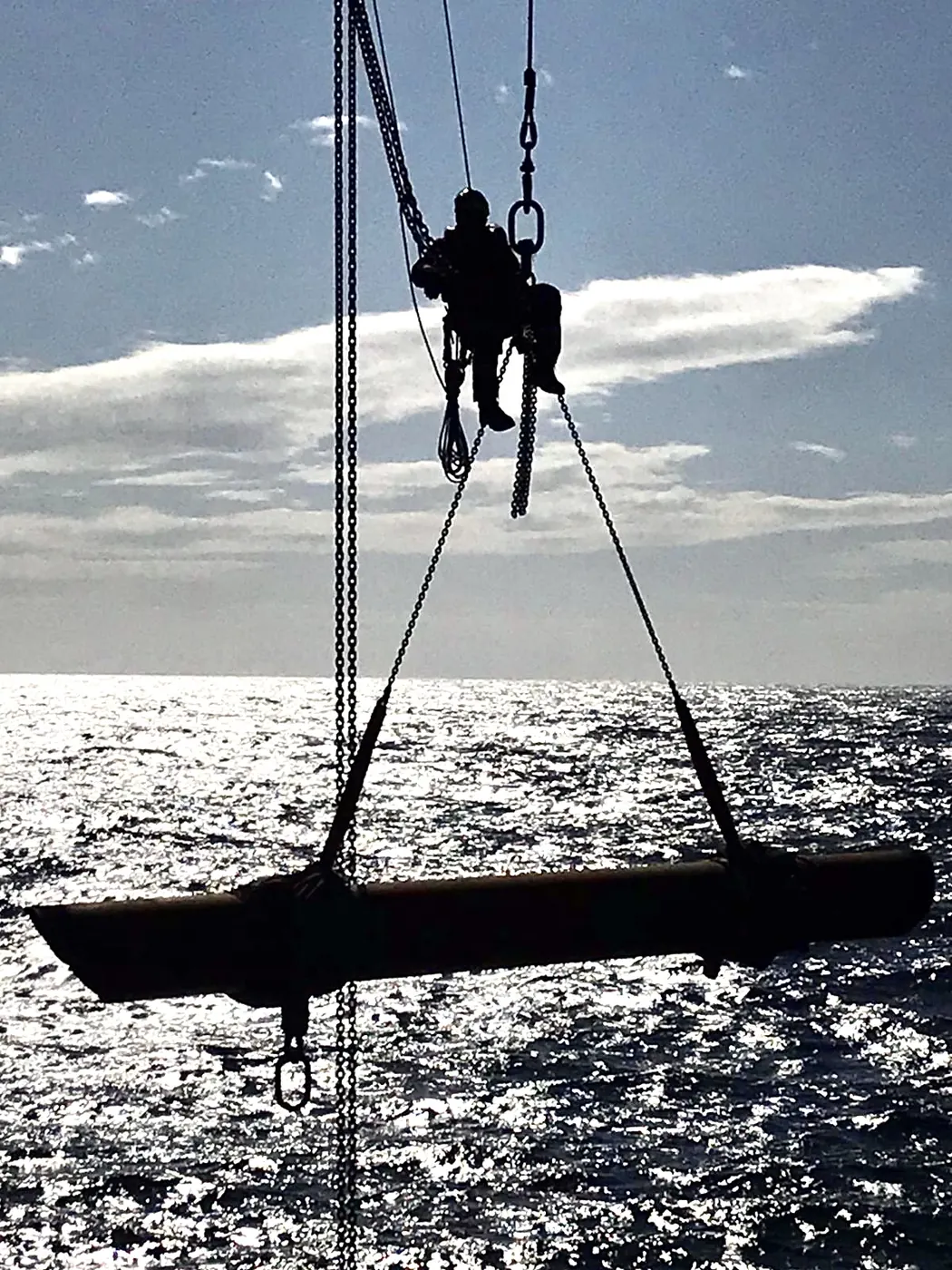 Silhouet van een rigger boven een hijslast op zee