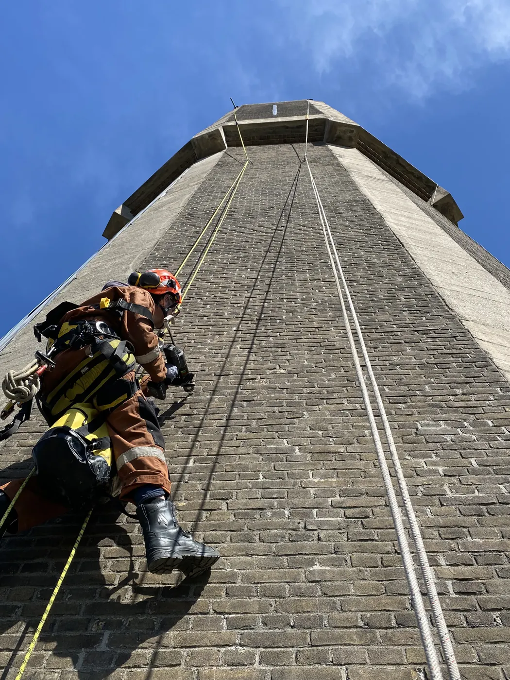 Klimmer werkt aan het metselwerk van een watertoren, opwaarts gefotografeerd